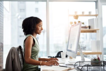 Woman in an office setting typing on a desktop computer