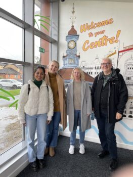 Four people stood in a line looking at the camera
