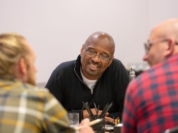 3 men sat talking to each other at a table
