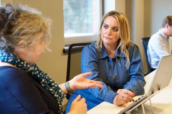 Two woman chatting at a desk