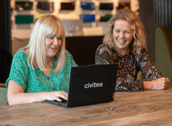 Two women sat chatting at a laptop
